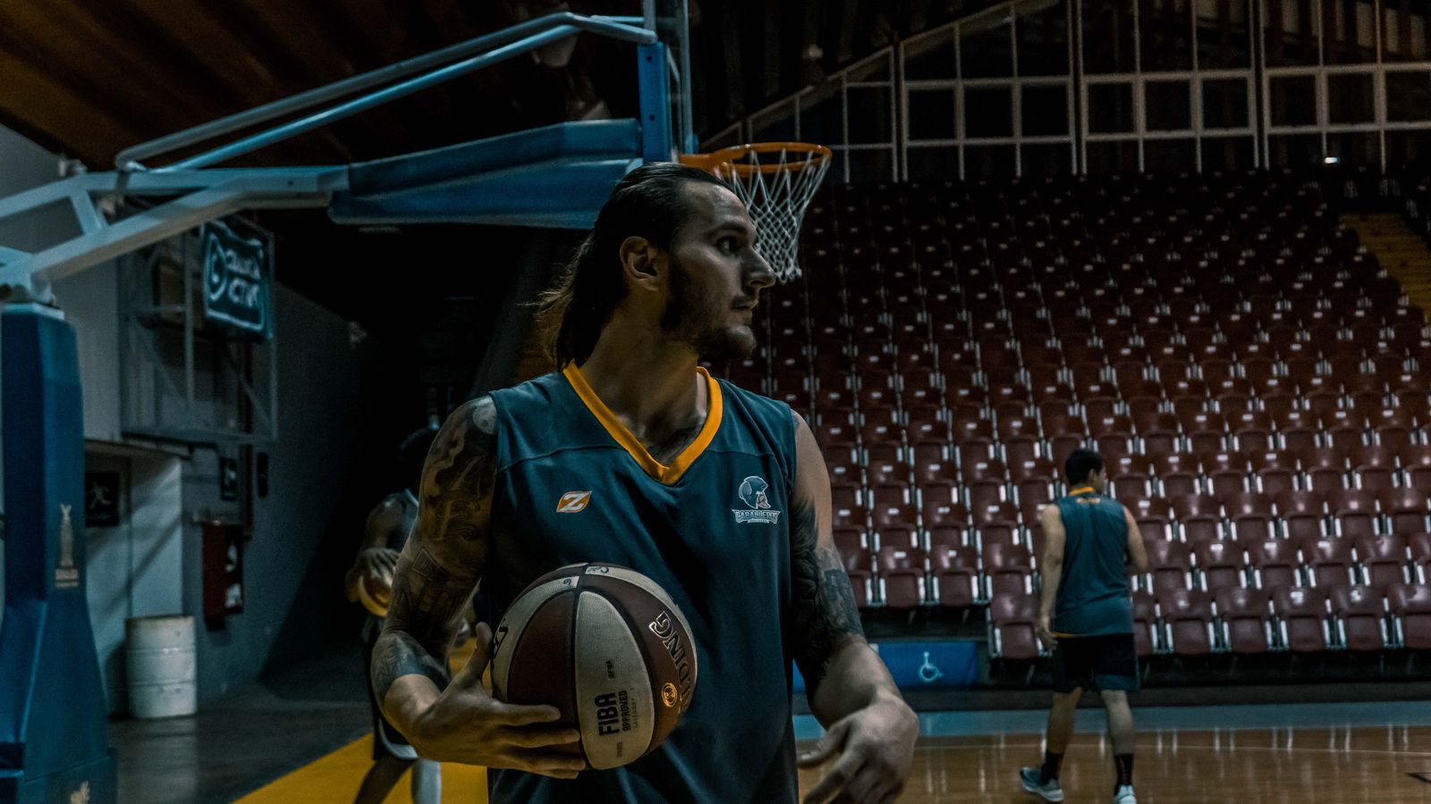 Male basketball players training and practicing in an indoor gym with basketballs and hoops.