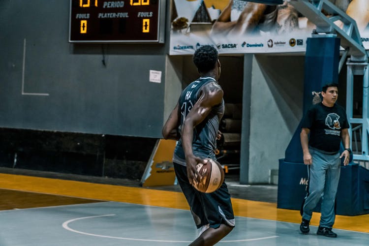 Man Holding Basketball On Blue Floor