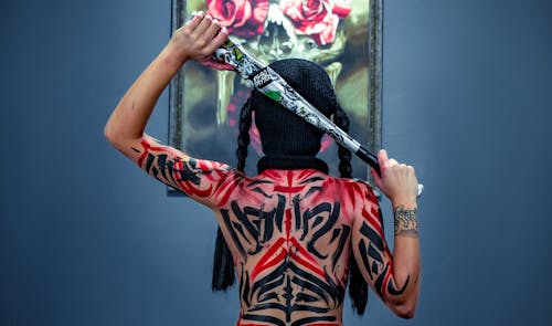 Free A Woman with Tattoos Holding a Baseball Bat Behind Her Head Stock Photo