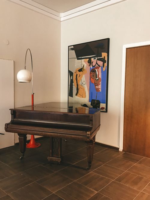Free A stylish room featuring a vintage piano, modern art, and minimalist decor. Stock Photo