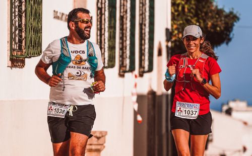Free Two athletes joyfully running in an outdoor trail race, enjoying the sunny day. Stock Photo