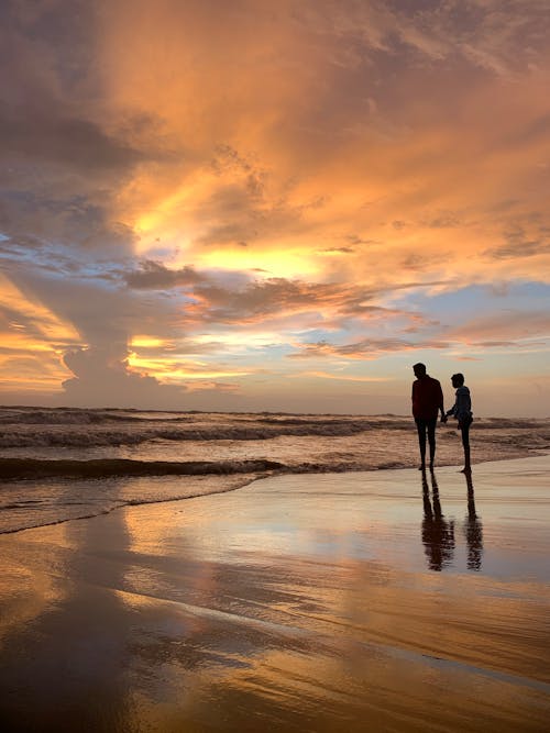 Silhouette of Two People Standing on the Beach during Sunset