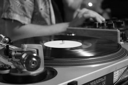Black and white image of a spinning vinyl record on a turntable, blending classic and modern music vibes.