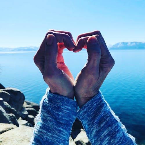 Person With Folded Hands Near Body of Water