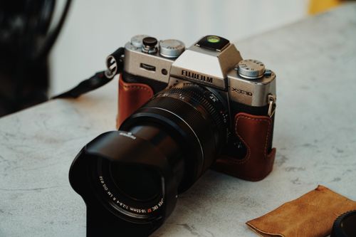 Free Close-up of a classic Fujifilm camera with strap, resting on a marble surface, artistic angle. Stock Photo