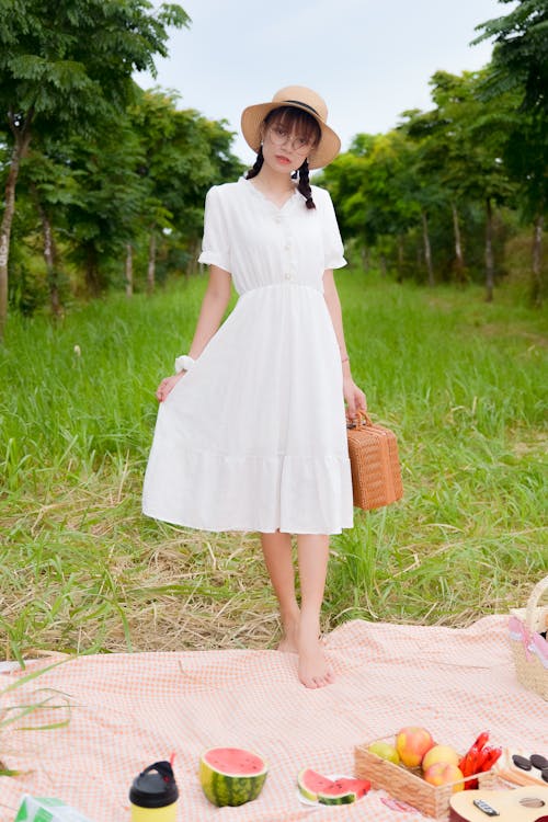 Free A Pretty Woman in White Dress Holding a Picnic Basket Stock Photo