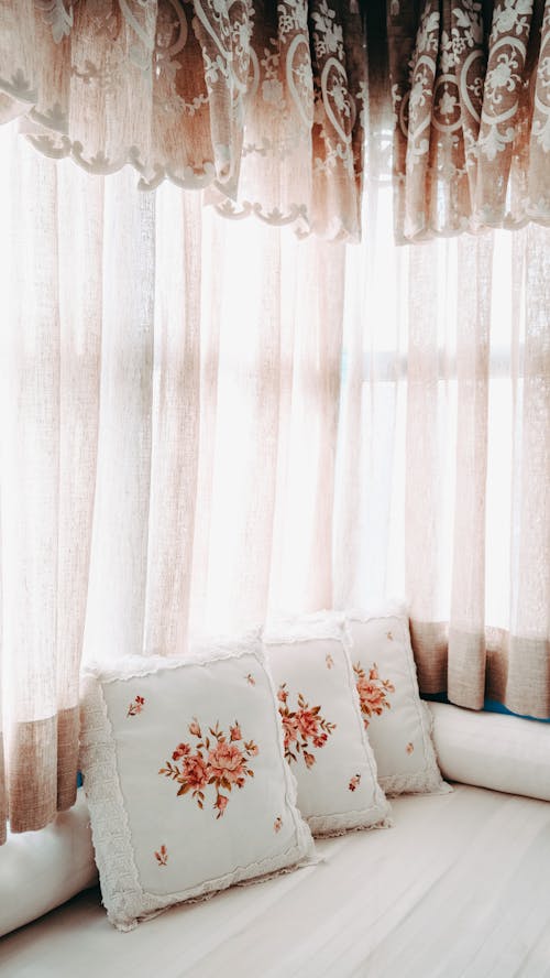 Free Pillows on bed and ornate window curtains Stock Photo