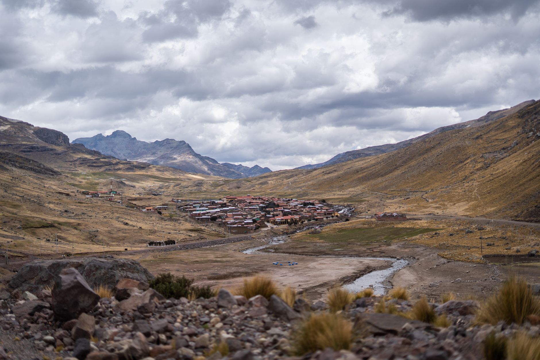 Overlooking a small village in a Peruvian valley with a cloudy sky backdrop.