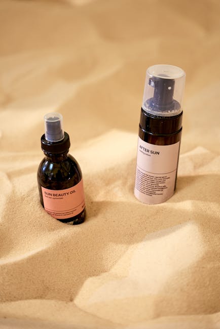 Sun beauty oil and after-sun cosmetic products placed on sand, ideal for skincare promotions.
