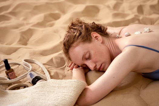 Woman relaxing on a sandy beach with seashells, exuding tranquility and summer vibes.