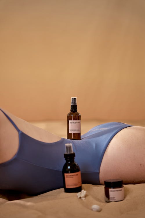 Free Cosmetic Product on a Person's Back while Lying on the Sand Stock Photo