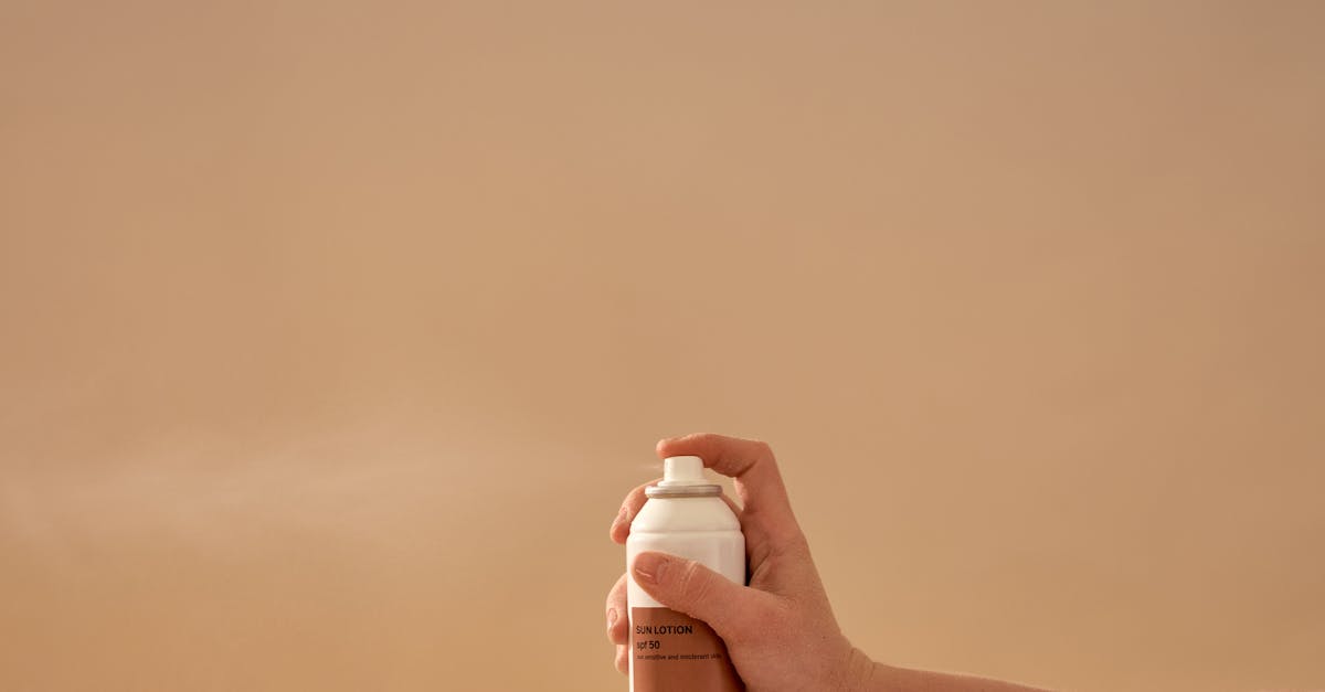 A person applying sunscreen lotion to their arm on a sunny beach.