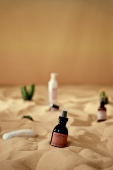 Artistic display of skincare products on sand, evoking a desert ambiance.