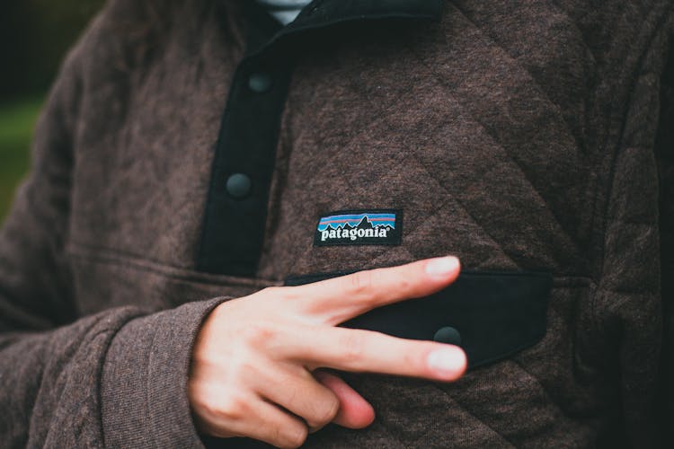 Person In Brown Sweater Doing A Peace Hand Signal