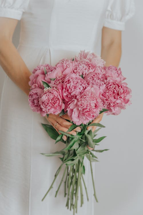 Woman in white dress holding pink bouquet