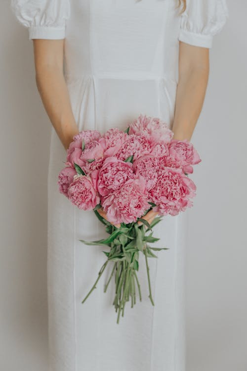 Woman in white dress holding pink flowers