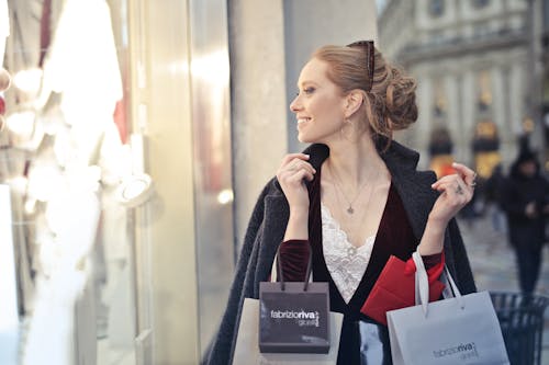 女人穿著黑色西裝外套拿著購物袋