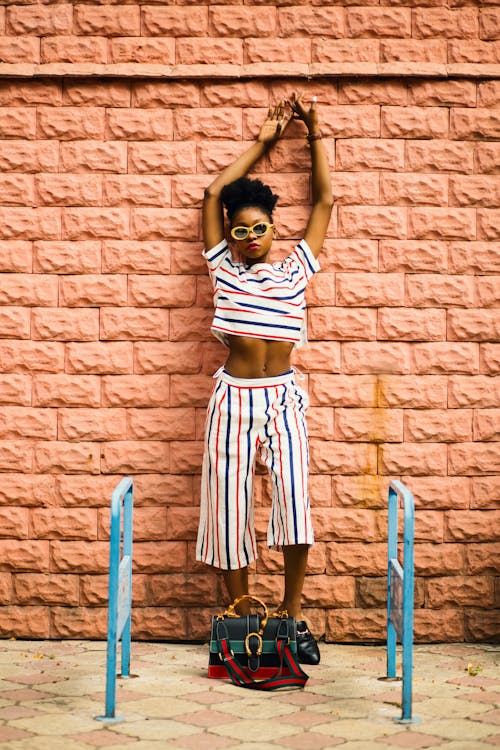 Woman in White, Blue, and Rd Shirt Leaning on Wall