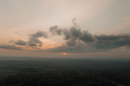 A tranquil aerial view showcasing a vast forest under a dramatic sunset sky.