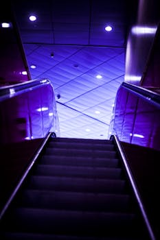 自动扶梯在鲜艳的紫色灯光映照下，呈现出戏剧性的镜头，营造出未来派的氛围