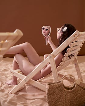 Woman on sunbed with mirror and straw bag in a relaxing beach setting.