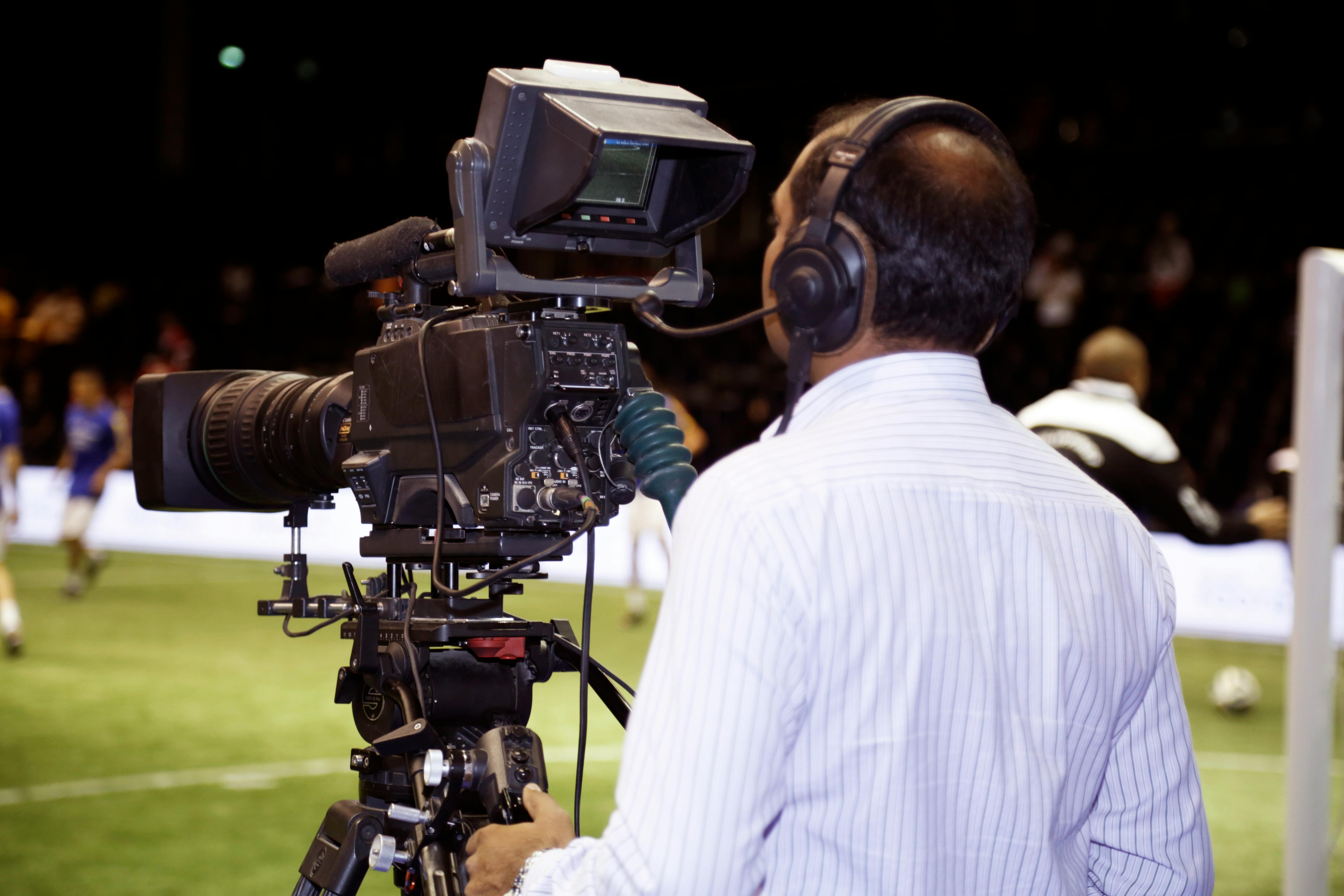 man with a tv camera filming a soccer match