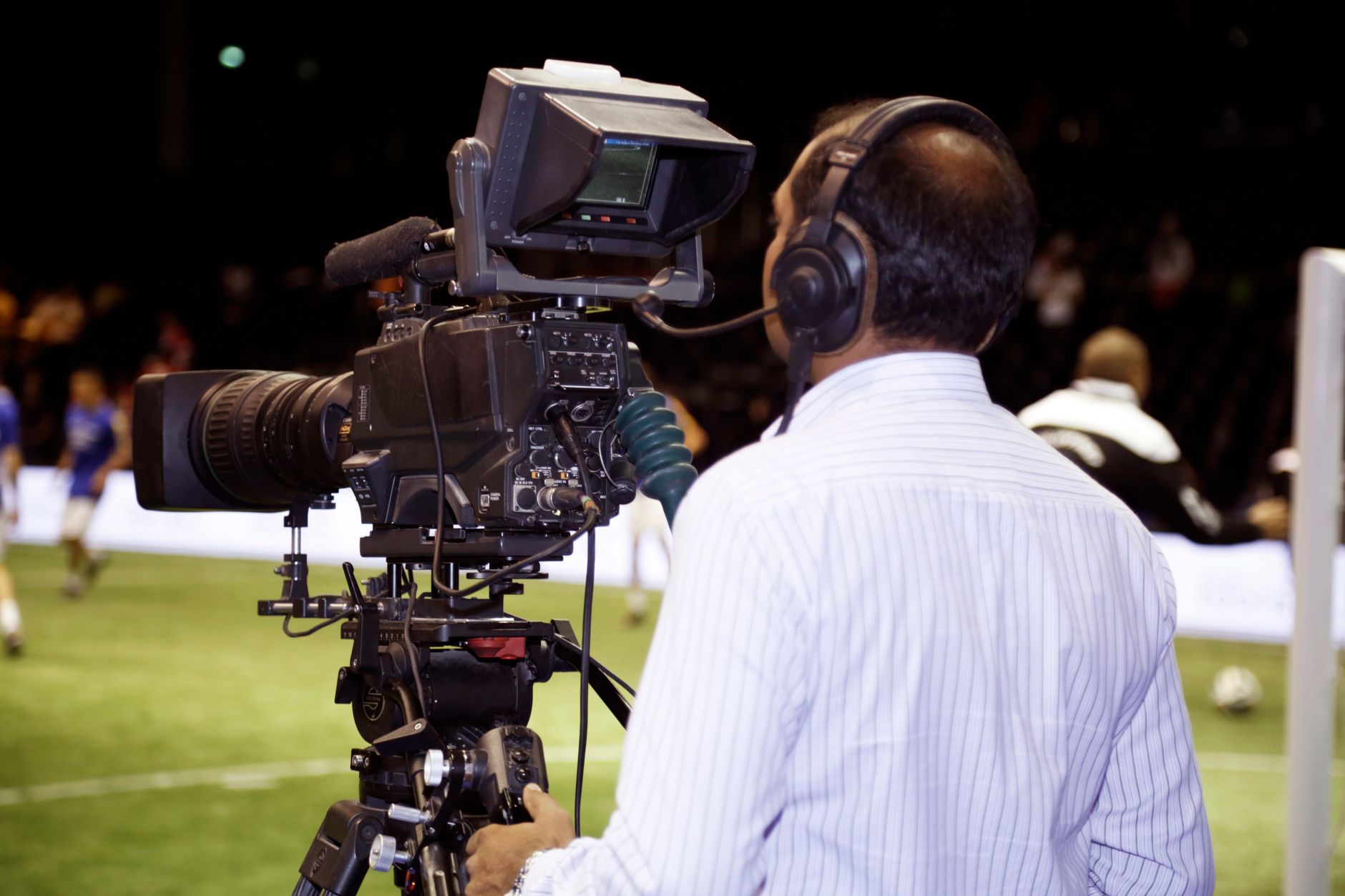 A cameraman filming a soccer match in a stadium, capturing the action on video.