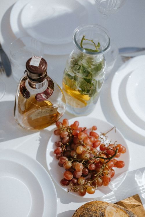 Free Beautiful table setting with grapes, a bottle, and infused water under sunlight. Stock Photo