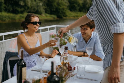 Friends enjoying a stylish outdoor brunch by the river on a sunny day.