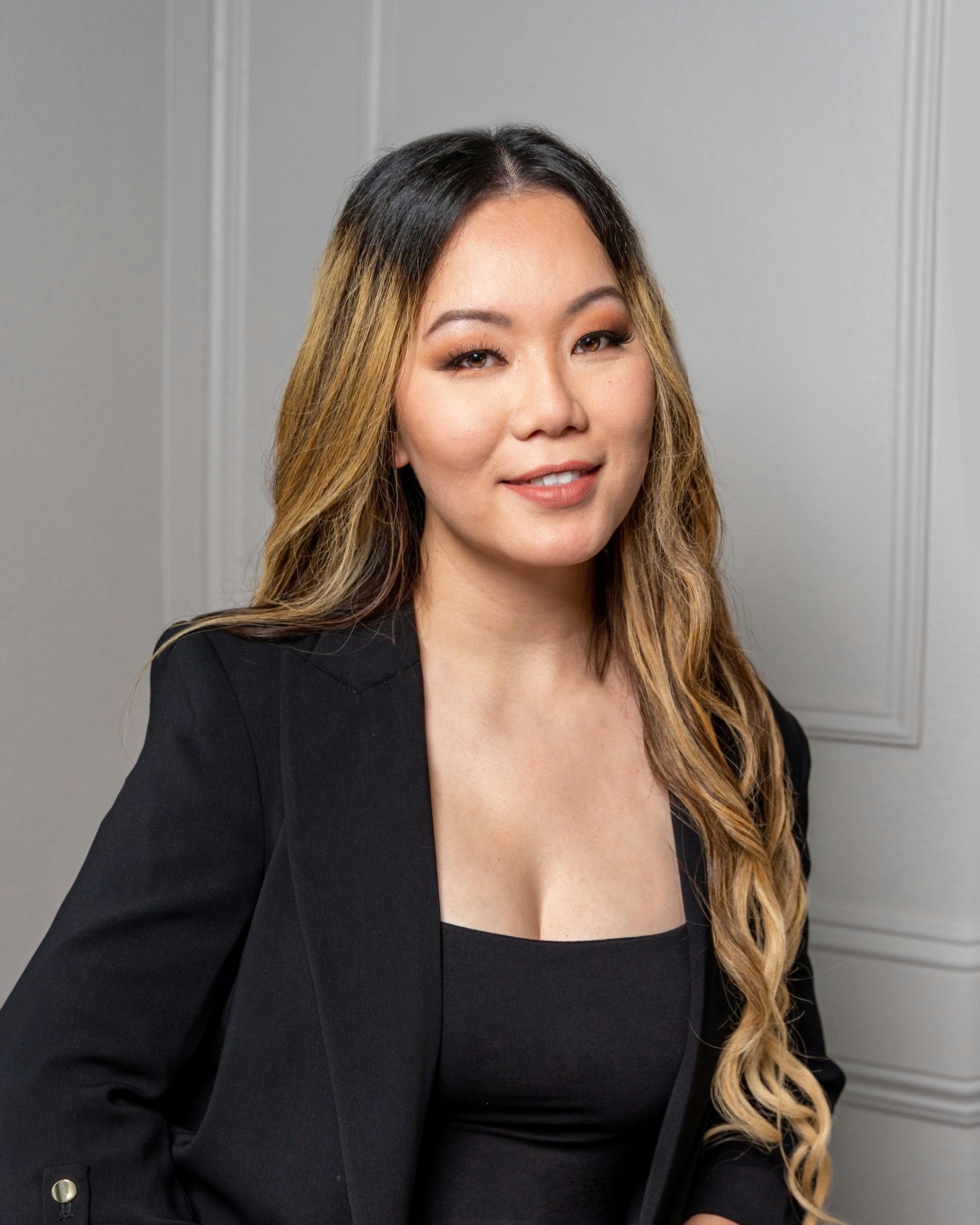 Elegant portrait of an Asian woman in a stylish black blazer indoors.