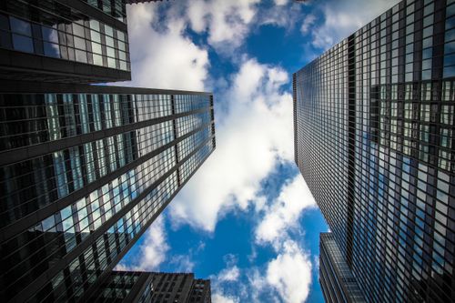 Free Low angle view of skyscrapers reaching towards a blue sky with clouds, showcasing modern architecture. Stock Photo
