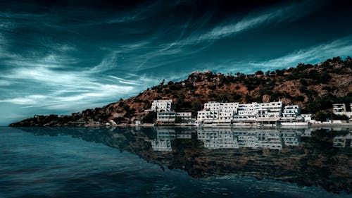 Základová fotografie zdarma na téma bílé budovy, bouřkové mraky, ostrovní pobřeží