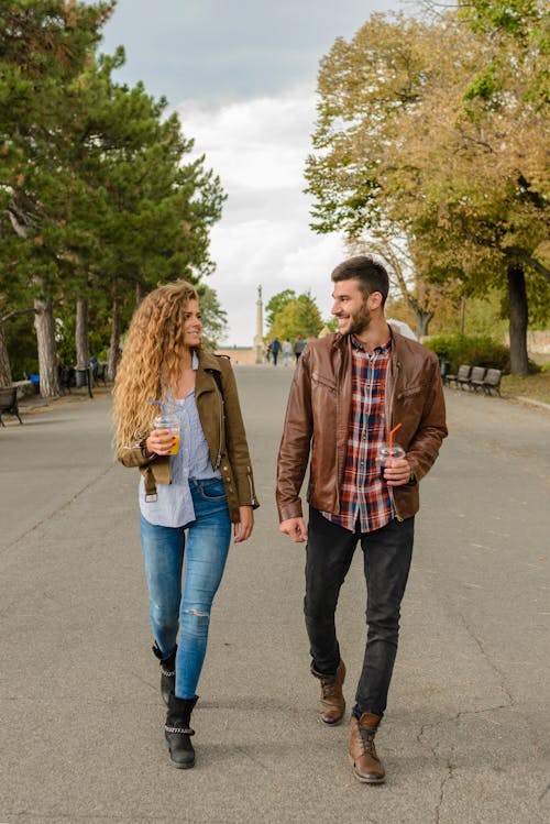 男人和女人穿着棕色外套在人行道上行走