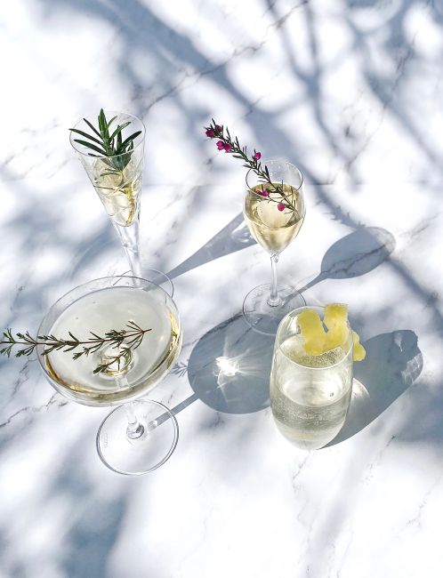 A selection of elegant cocktails with garnishes on a marble table, casting artistic shadows.