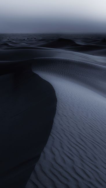 Dark and serene view of desert sand dunes under a night sky in Al Madam, UAE.