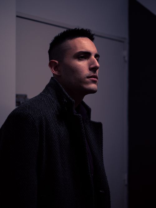 Free A thoughtful man in a dark coat, captured indoors with moody lighting. Stock Photo