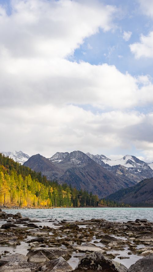 Free Beautiful landscape of a mountain lake with lush forests and dramatic clouds. Stock Photo