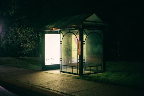 Free A bus stop illuminated at night on a quiet sidewalk, creating a serene urban scene. Stock Photo