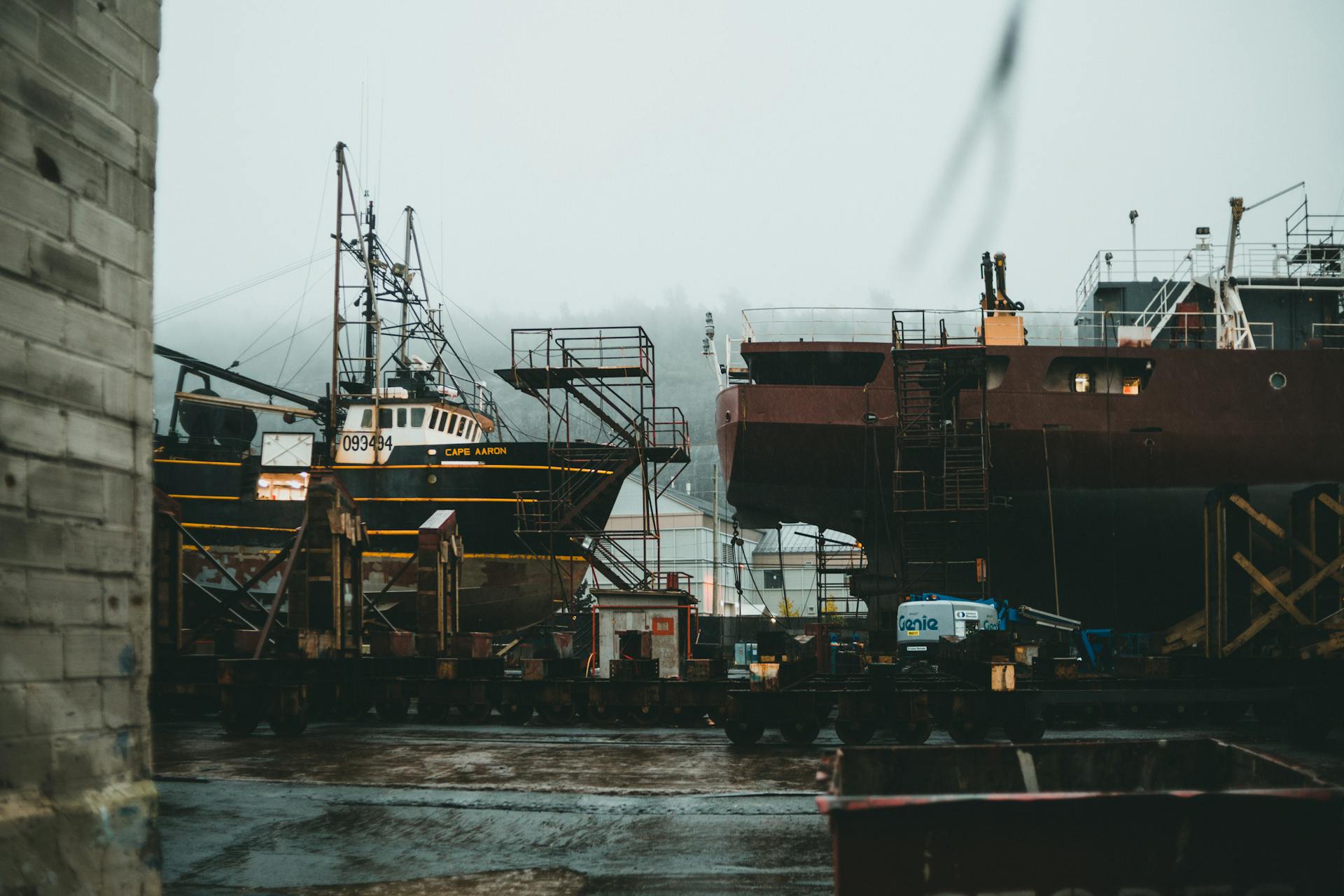 A shipyard with docked vessels and industrial structures on a foggy day.