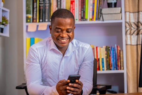 Man in White Long Sleeve Shirt Using a Cellphone