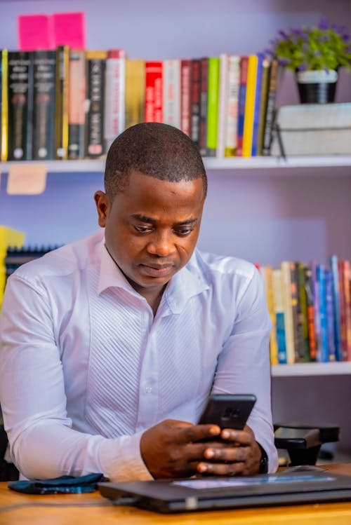 Man in White Long Sleeve Shirt Using Cellphone