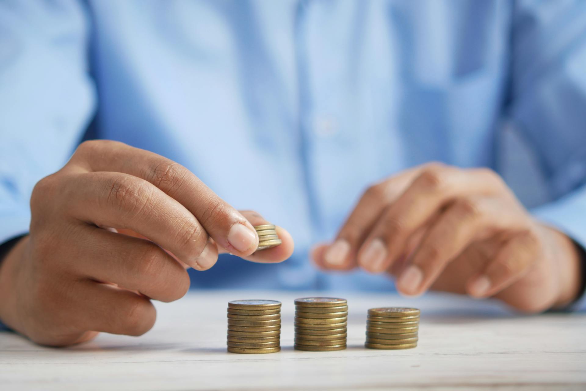 Close-up of hands stacking gold coins, symbolizing financial growth and savings.