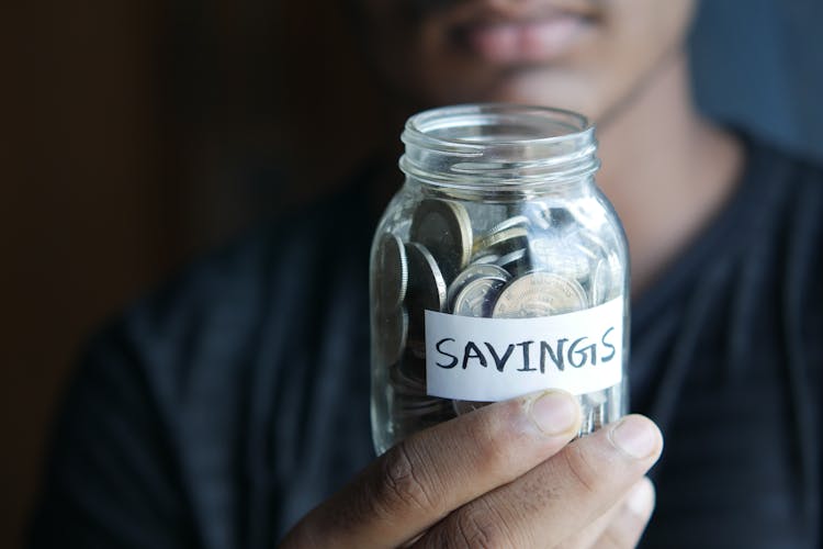 Close-Up Shot Of A Person Holding A Jar With Coins