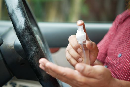 Close-up of a person sanitizing hands in a car for hygiene.