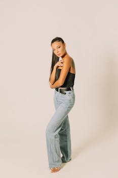 Young woman wearing jeans and tube top posing in a studio with a neutral background.