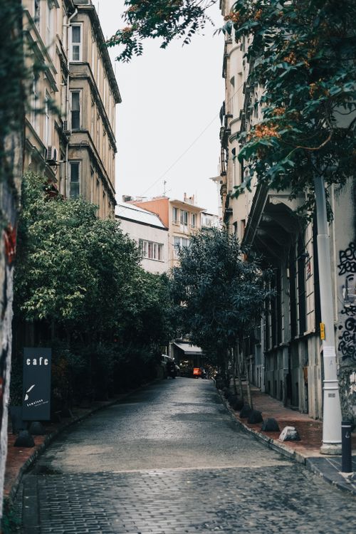 Free A picturesque narrow street lined with historic buildings and lush greenery, capturing urban charm. Stock Photo