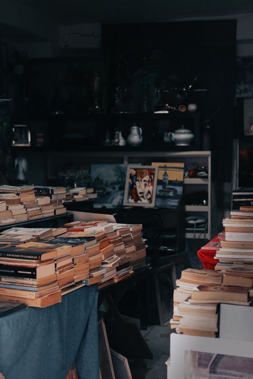 Free A dimly lit bookstore featuring a vast collection of stacked books and vintage decor. Stock Photo