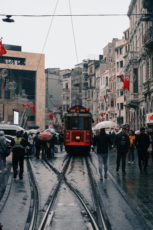 People Walking on the Street near a Red Tram