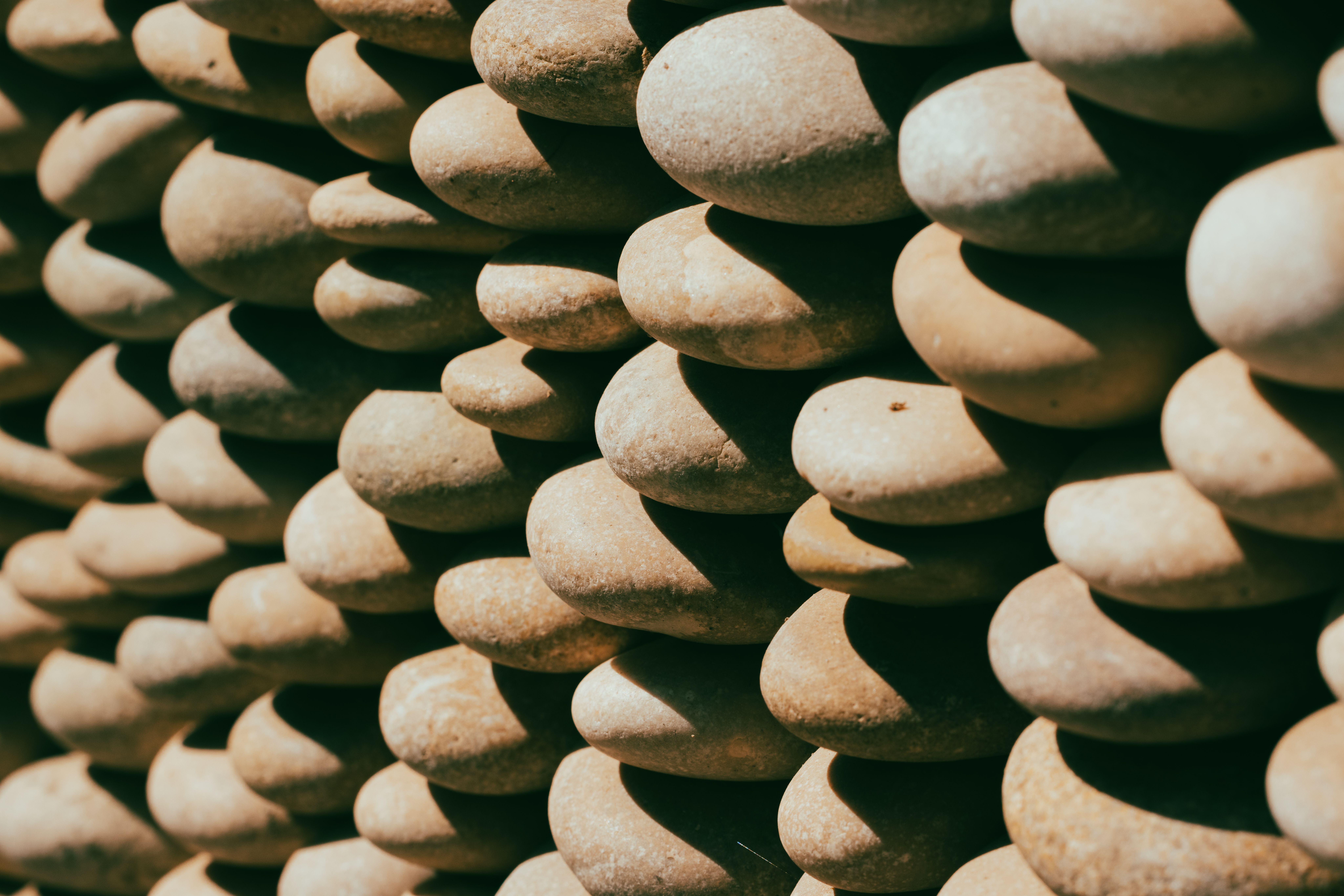 Close-up of smooth river stones stacked in balance against a warm amber backdrop, no faces