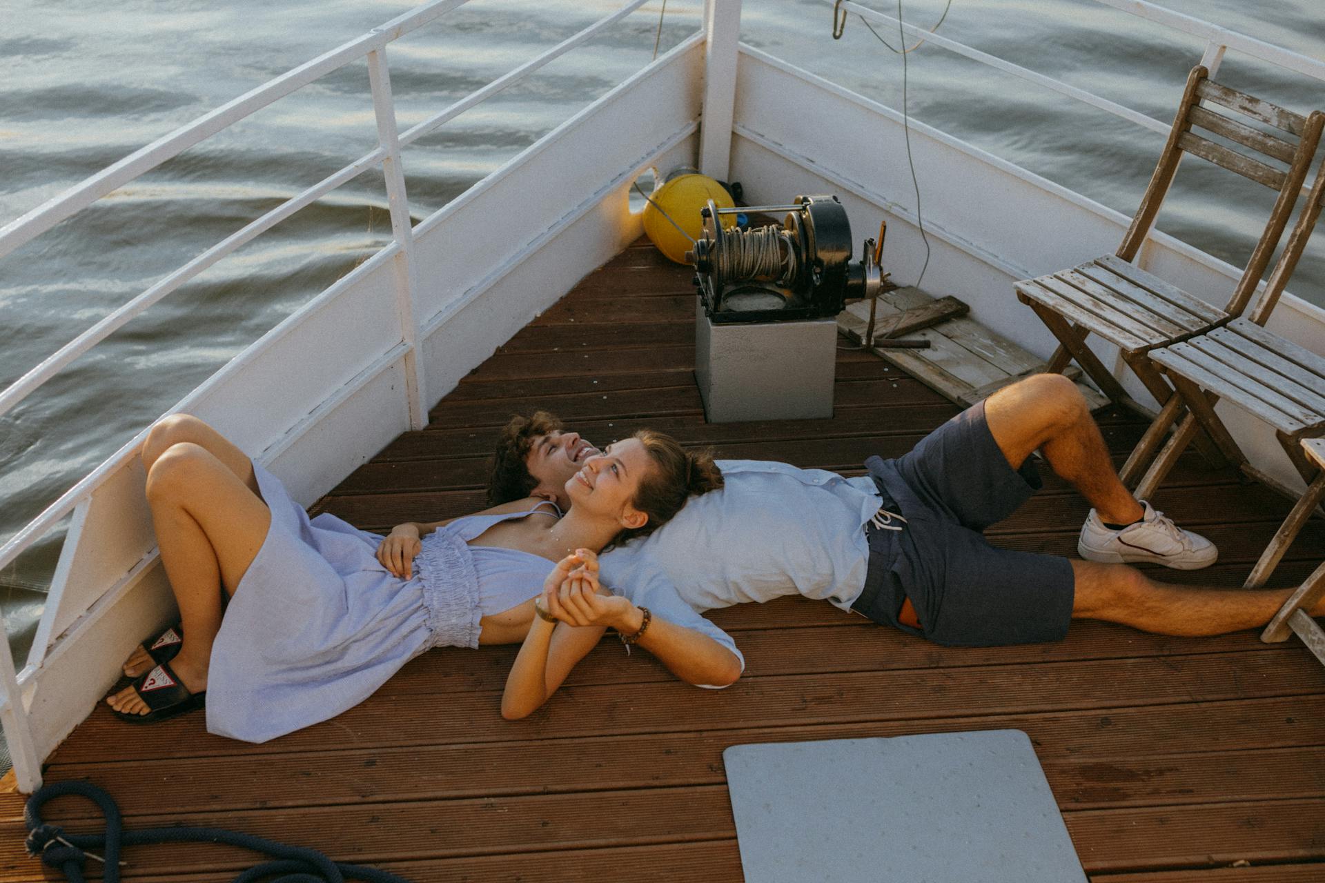 A couple enjoys a romantic moment on a boat deck during sunset, highlighting love and relaxation.